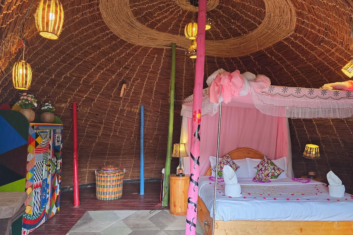 A tent-style room with a bed, hanging lights, and a colorful wall decoration.