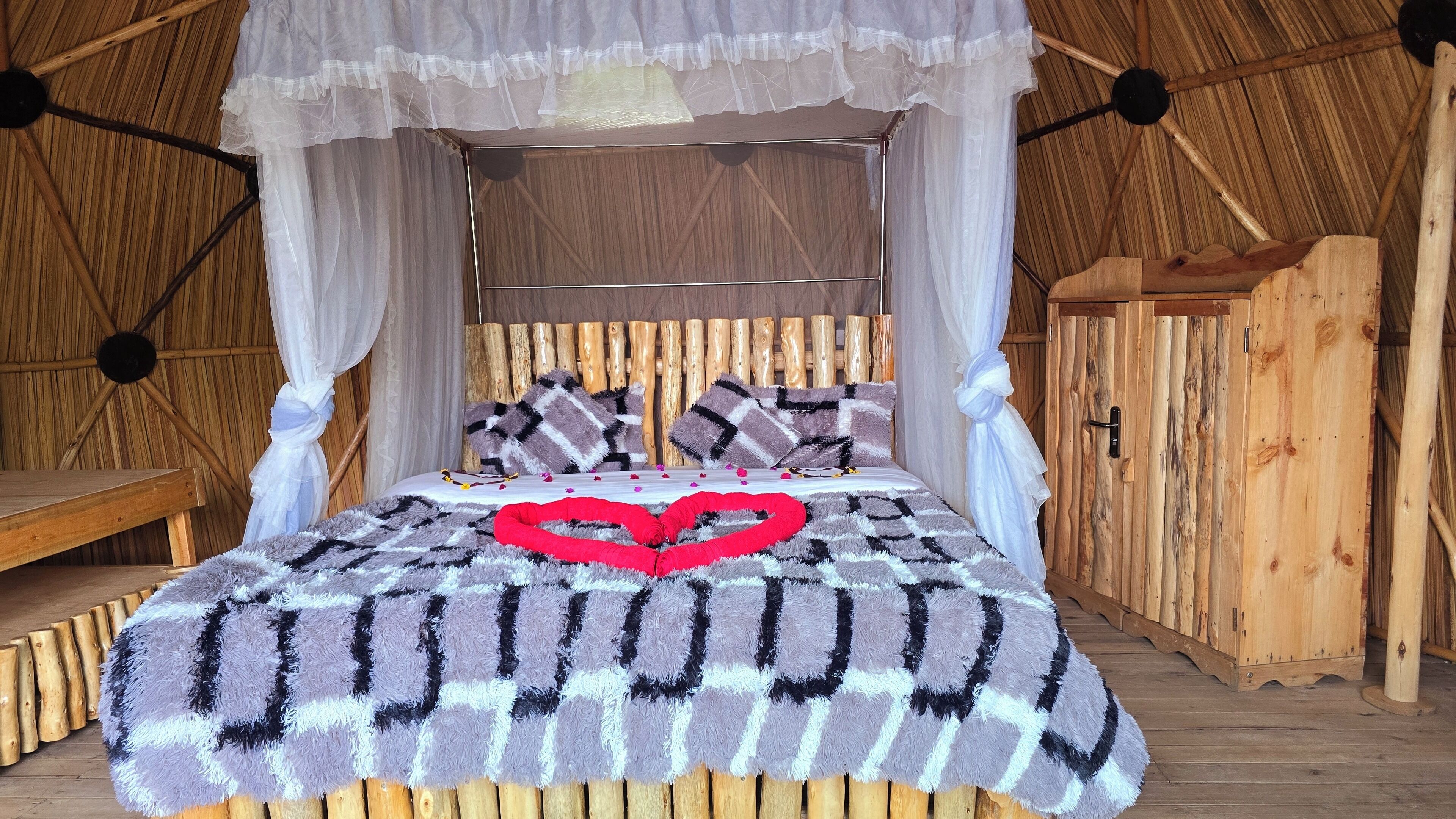 Una cama con dosel, paredes de madera y un banco.