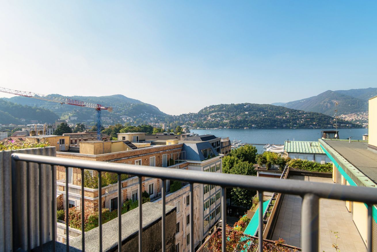 Ein Balkon mit Blick auf einen See, Gebäude und Berge.