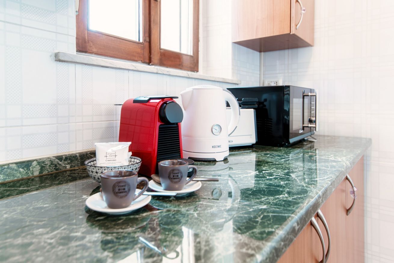 A kitchen with a coffee maker, toaster, and cups on the counter.