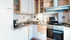 A modern kitchen with white cabinets, a stainless steel range, and a microwave. - Celeste - My Home In Como (Como)