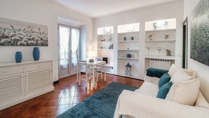 A modern living room with a sofa, a dining table with chairs, a kitchen area, and a large window. - Celeste - My Home In Como (Como)