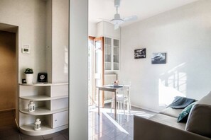 A modern living room with a sofa, a dining table, and a ceiling fan. - Finestra sul Lago - My Home In Como (Cernobbio)