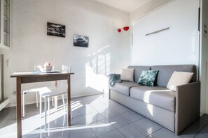 Un salon moderne avec un canapé, une table à manger et des chaises, ainsi que deux tableaux accrochés au mur.