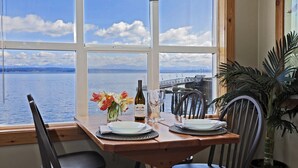 A dining table set for two with a view of a lake and a bridge.