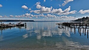 A calm waterfront with docks and boats, clear skies, and distant land.