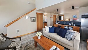 A modern living room with a sofa, coffee table, and a staircase leading to an upper level.