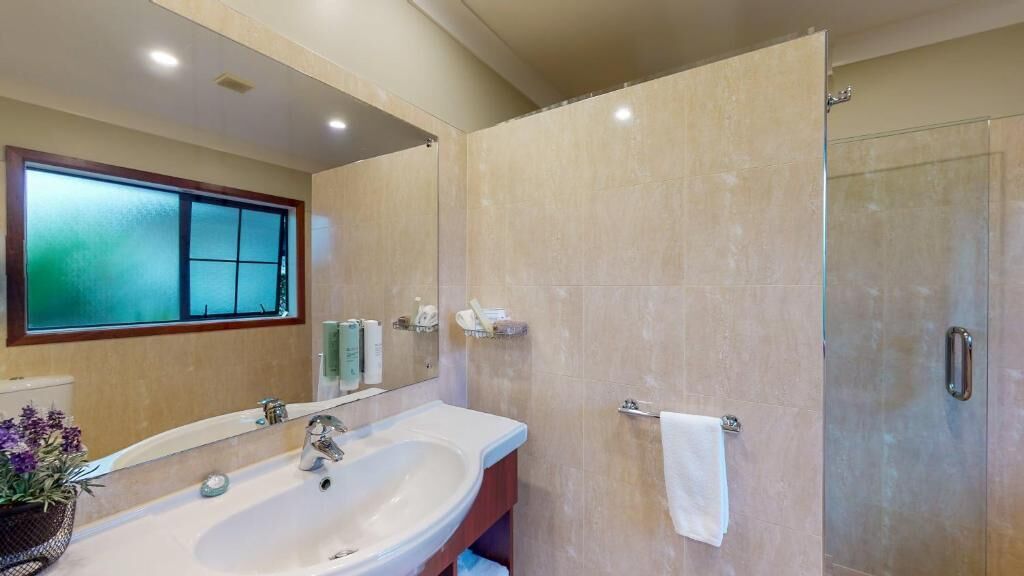 A bathroom with a large sink, mirror, and a glass shower enclosure.