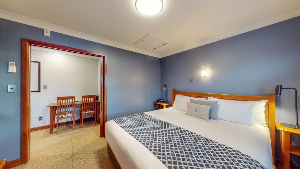 A bedroom with a bed, a desk, and a chair.