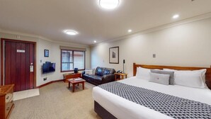 Una habitación de hotel con una cama grande, un sofá, un escritorio y un televisor.