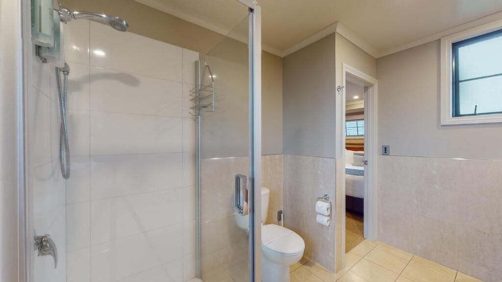 A modern bathroom with a glass-enclosed shower, a toilet, and a sink.