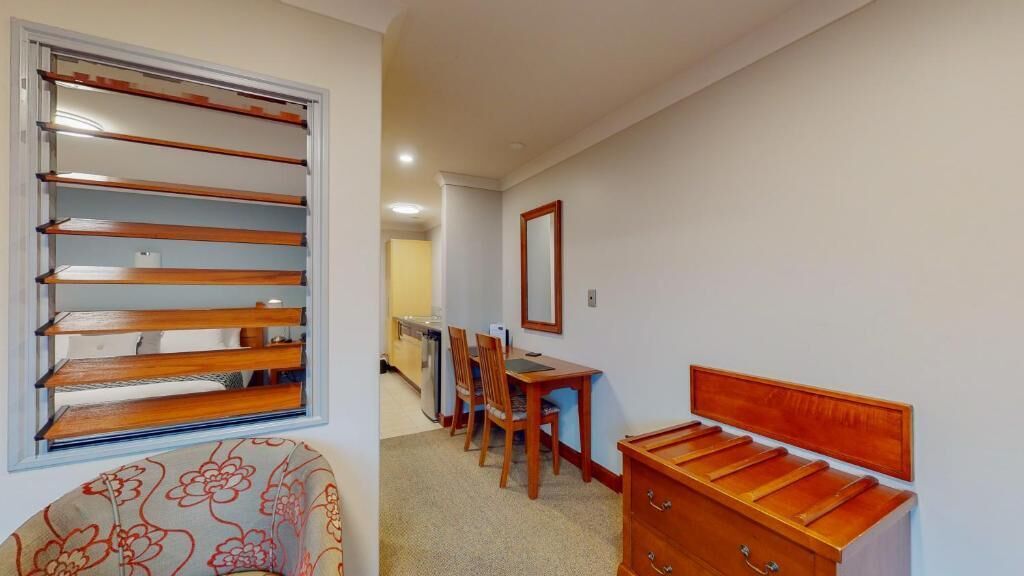 A bedroom with a wooden headboard, a desk, and a chair.