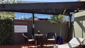 Un patio con piscina, sillones de descanso y una mesa con sillas.