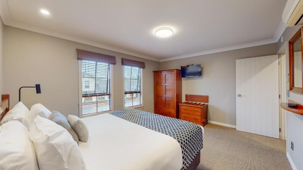 Un dormitorio con una cama, un aparador, un televisor y un armario.