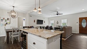 A spacious kitchen with a granite countertop, white cabinetry, and a dining area with a table and chairs.