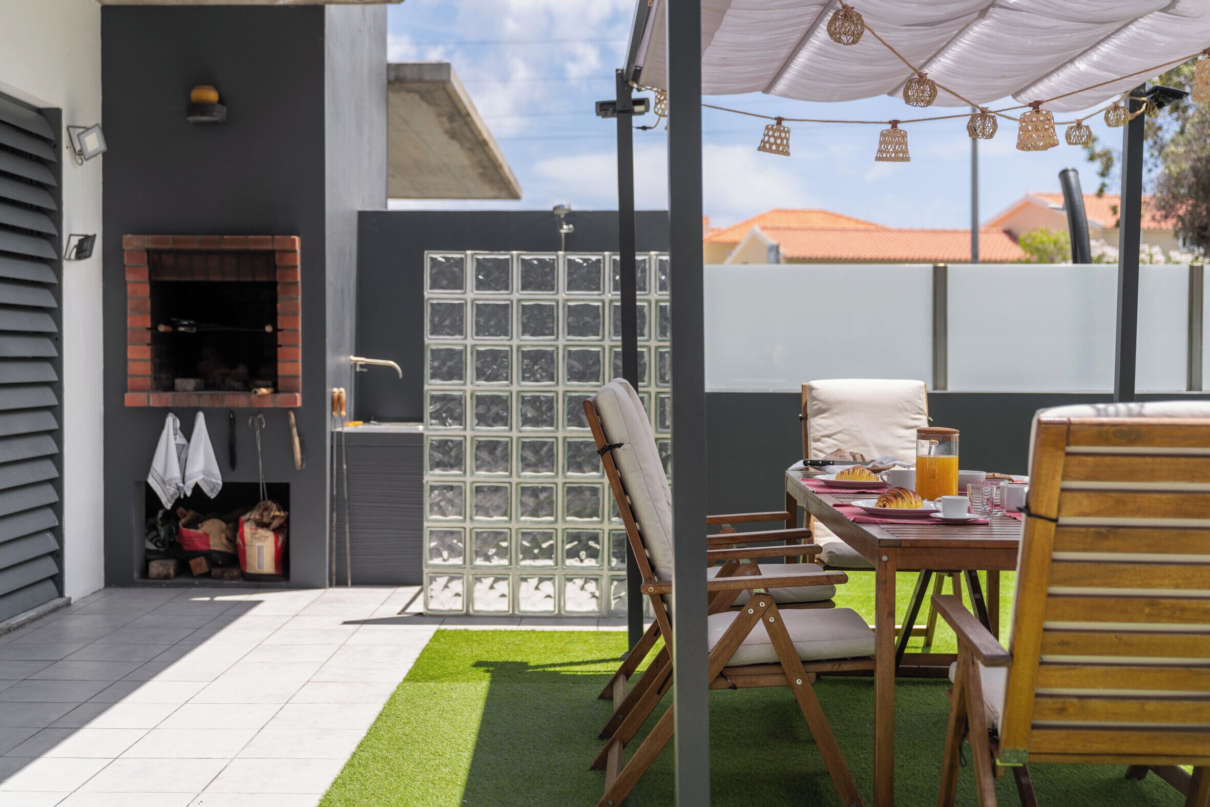 Eine Terrasse im Freien mit Esstisch, Stühlen und Grillplatz.
