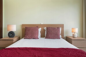 A hotel room with a bed, two nightstands, two lamps, and a red blanket. - Vacation home in Porto Santo, Villa Girassol (Porto Santo)