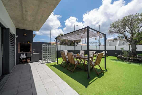 A patio with a table and chairs, a grill, and a covered seating area.