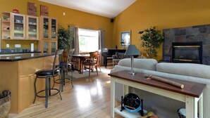 A kitchen with wooden cabinets, a dining area with a table and chairs, a living room with a sofa, and a fireplace. - Amazing Home...Large Space Yet Cozy (Kirkland)