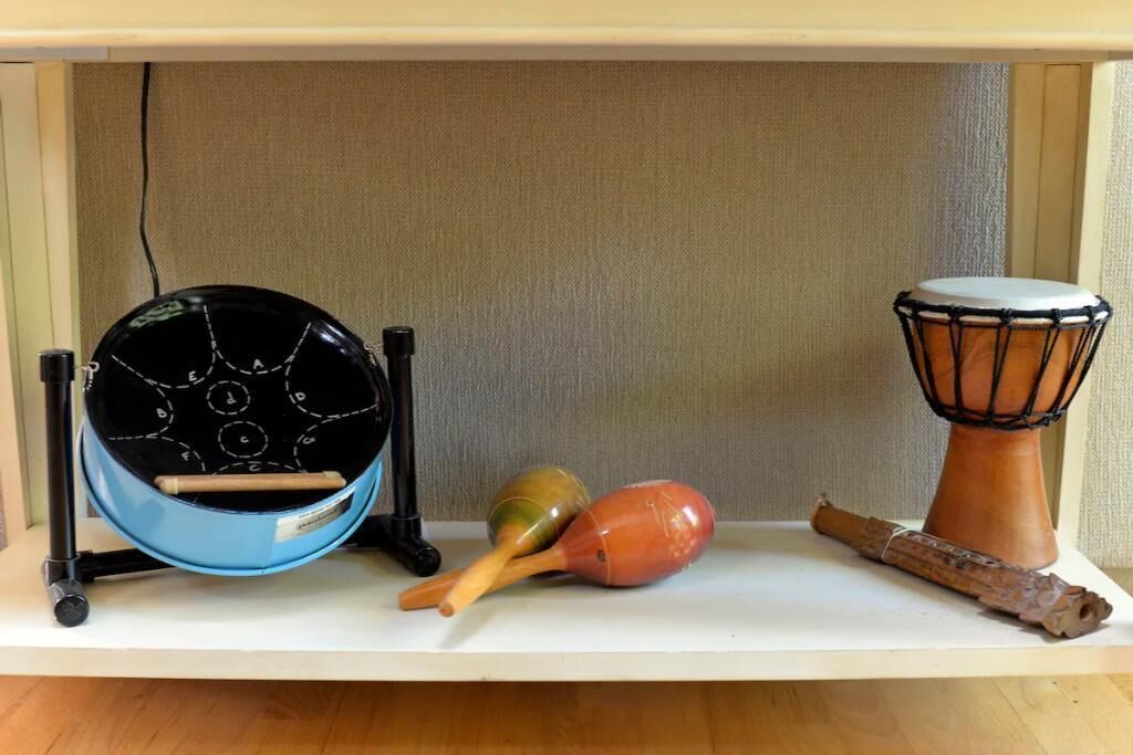 Une étagère avec un tambour bleu, une paire de maracas, un tambour en bois et une baguette de batterie.