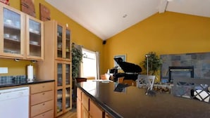 A kitchen with wooden cabinets, a black countertop, and a stone fireplace. - Amazing Home...Large Space Yet Cozy (Kirkland)