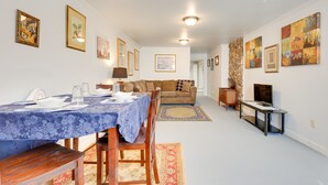 A dining area with a table set for four, a sofa, a television, and framed artwork on the walls. - Comfortable Alabama Apartment: Pets Welcome! (Jackson)