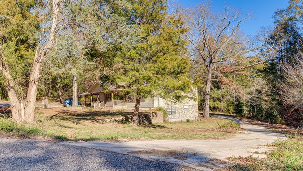 A house surrounded by trees, a driveway, and a blue car parked nearby. - Comfortable Alabama Apartment: Pets Welcome! (Jackson)