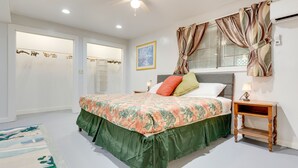A bedroom with a bed, a nightstand, a ceiling fan, a window with curtains, and a door with a towel rack. - Comfortable Alabama Apartment: Pets Welcome! (Jackson)