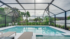 Une piscine extérieure couverte, dotée de chaises longues et d’une table en verre.
