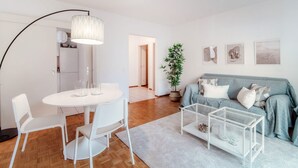 Una sala de estar moderna con comedor, un sofá gris y una planta en maceta.