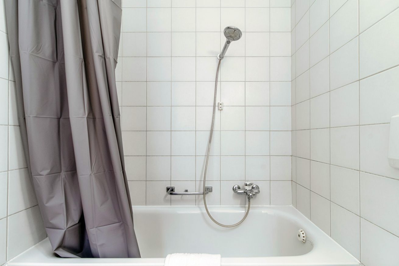 Un bagno moderno con vasca, doccia e tenda grigia.
