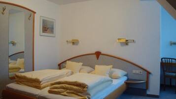 A bedroom with a bed, a chair, a mirror, and a wall-mounted light fixture.