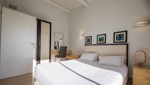 A modern hotel room with a large bed, a desk, and a chair. There are three framed pictures on the wall above the bed.