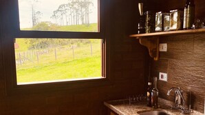 A kitchen with a window, wooden cabinets, a granite countertop, and a sink.