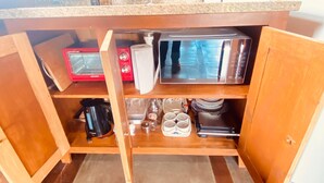 A kitchen with a wooden countertop, a microwave, a coffee maker, and a sink.