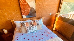A bed with a white textured bedspread, a heart-shaped arrangement of rose petals, and towels.