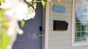 Huisnummer 633 op een lichtblauwe deur met een 'hello'-bord.