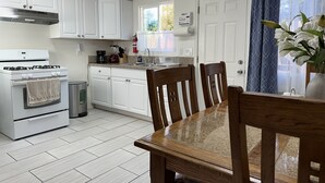 A kitchen with white cabinets, a stove, and a dining table with chairs. - CocoVilla Apartment #2 (Santa Barbara)
