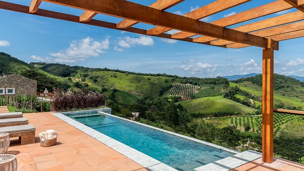 A pool area with a pergola, outdoor seating, and a view of rolling hills. - Vista Deslumbrante e Alto Padrão com 4 Suites, Piscina Aquecida e Sauna (Santo Antônio do Pinhal)