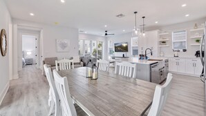 Una cocina moderna con armarios blancos, una isla central e iluminación colgante.