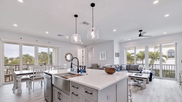 Una cocina amplia con una isla grande, armarios blancos e iluminación colgante.