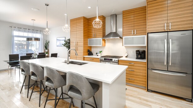 A modern kitchen with a central island, stainless steel appliances, wooden cabinets, and a large window providing natural light. - Detached, Luxury, mins to DT & Walking distance to C-train! (Calgary)