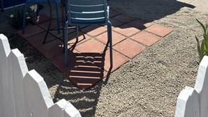 Una casa con porche cubierto, un pequeño patio con mesa y sillas, y un camino de entrada de grava.