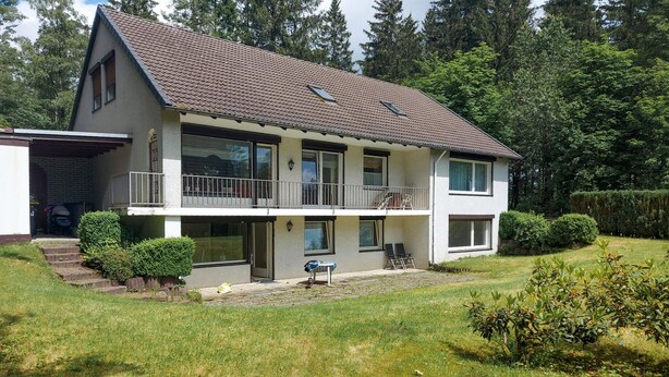 A two-story house with a balcony, a covered outdoor seating area, and a well-maintained lawn. - Cozy apartment in Goslar OT Hahnenklee with WiFi (Goslar OT Hahnenklee)
