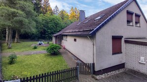 A single-story house with a sloped roof, a small porch, and a fenced yard. - Cozy apartment in Goslar OT Hahnenklee with WiFi (Goslar OT Hahnenklee)