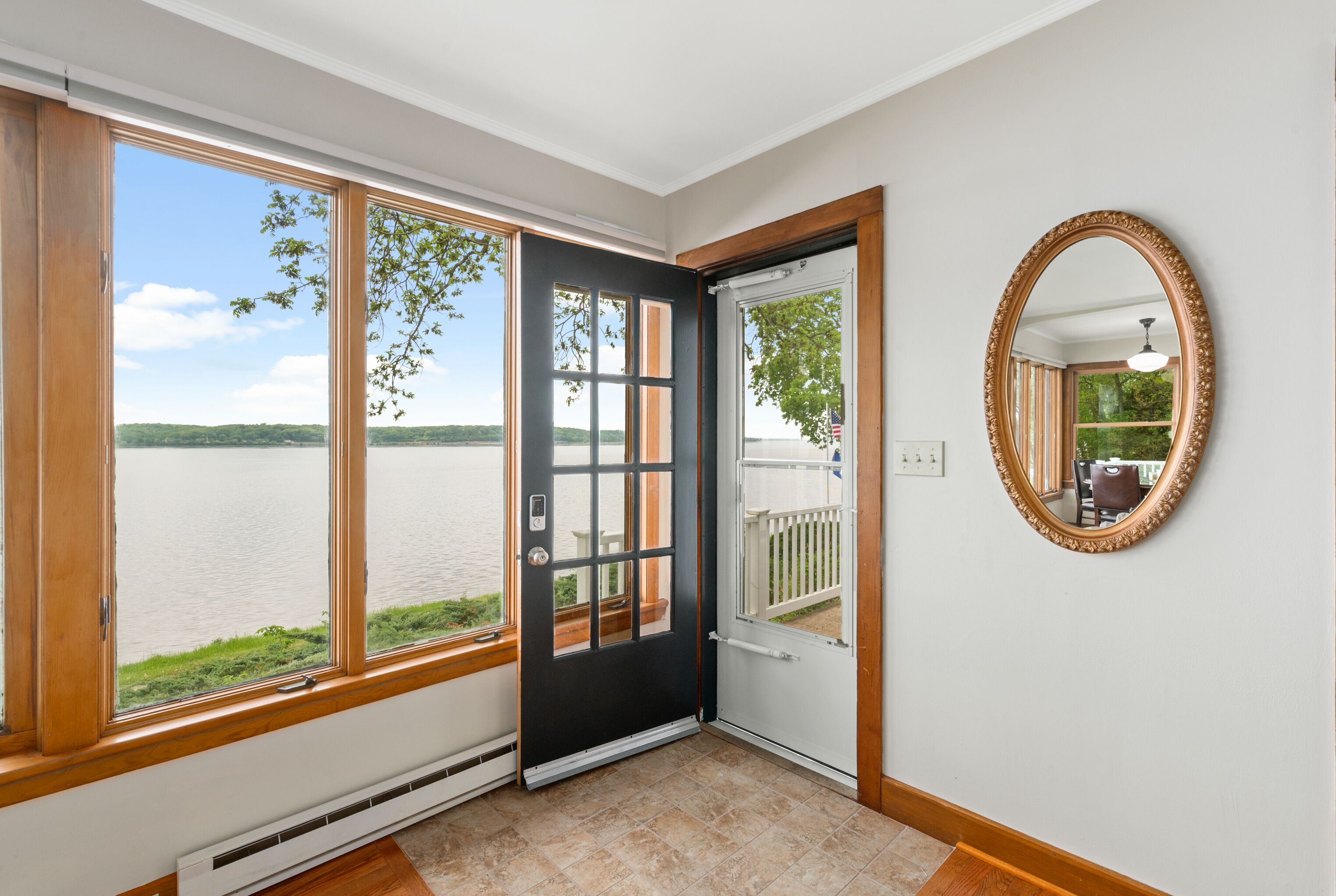 A room with a large window, a door, and a mirror on the wall.