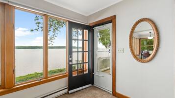 A room with a large window, a door, and a mirror on the wall.
