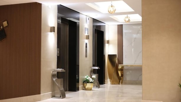 A modern hotel lobby with a marble floor, a reception desk, and a potted plant. - Mabit Rahhal Serviced Apartments (Yanbu)