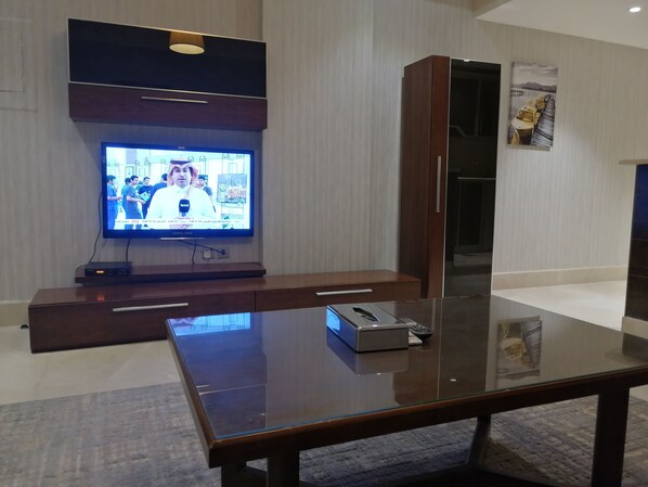 Una sala de estar moderna con un televisor de pantalla plana, muebles de madera y una mesa de centro de vidrio.
