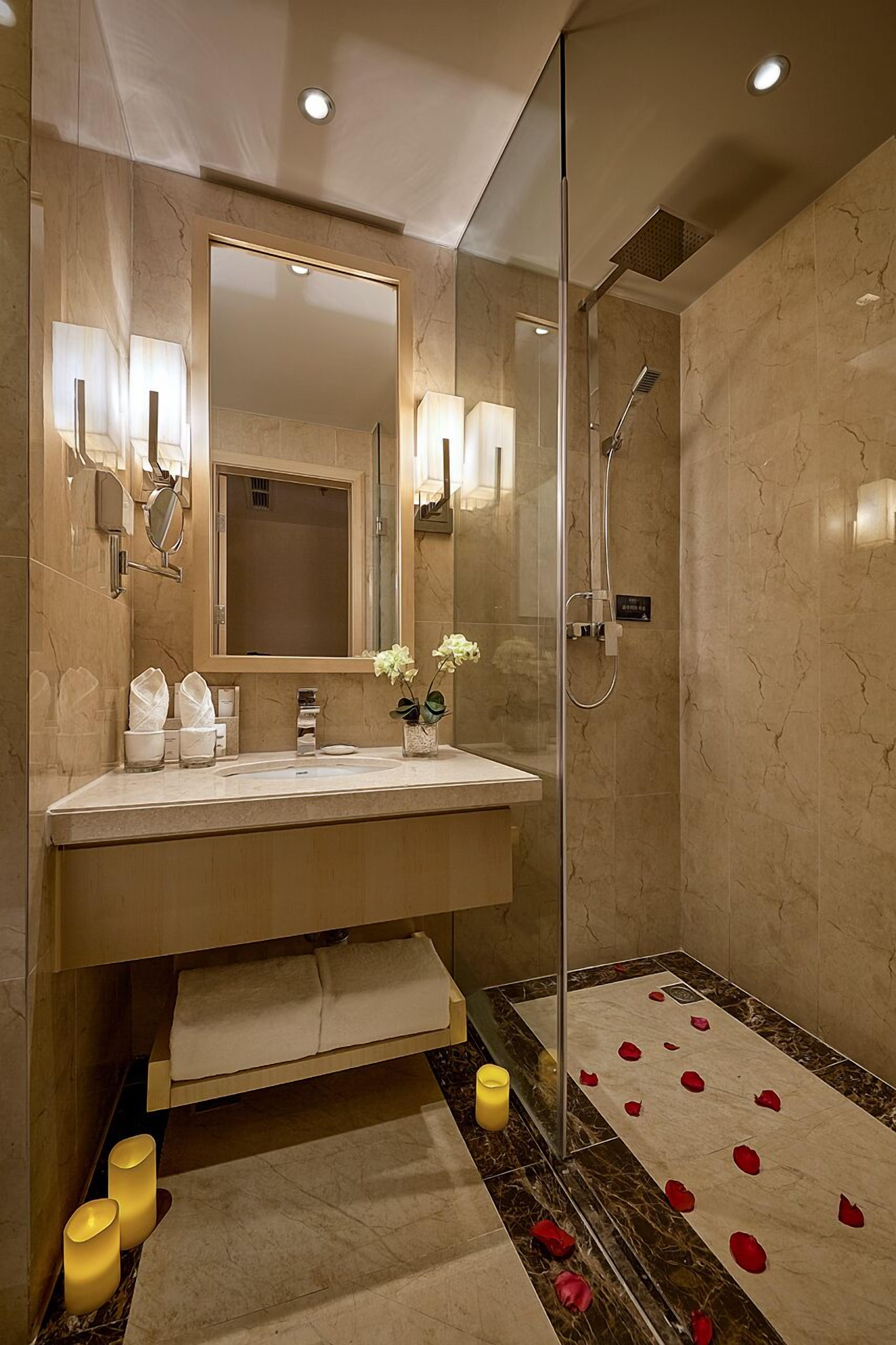 A modern bathroom with a large mirror, a sink, and a shower.